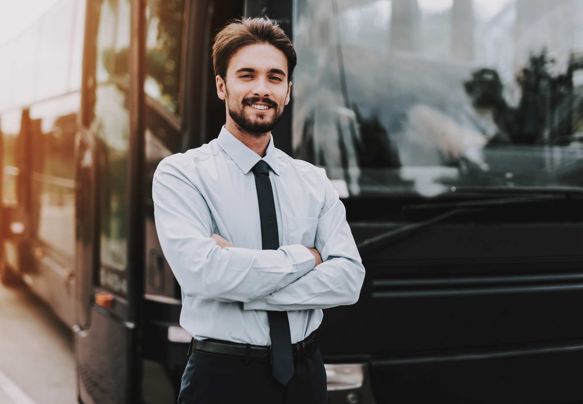 professional corporate chauffer in front of a motor coach
