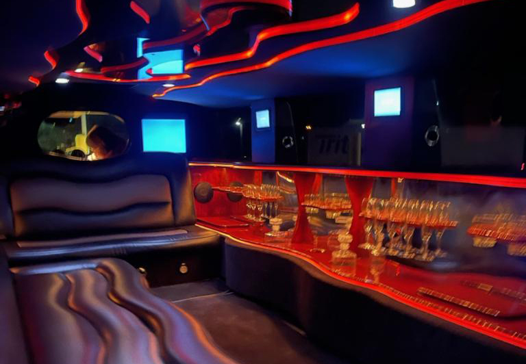 stretch Hummer limousine interior with bench seating, built in bar with champagne glasses and accent lighting
