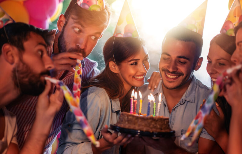 group celebrating a birthday with birthday hats and cake