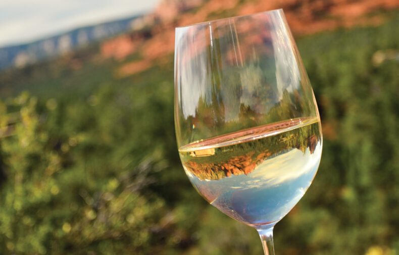 wineglass filled with wine in front of view of Sedona red rocks