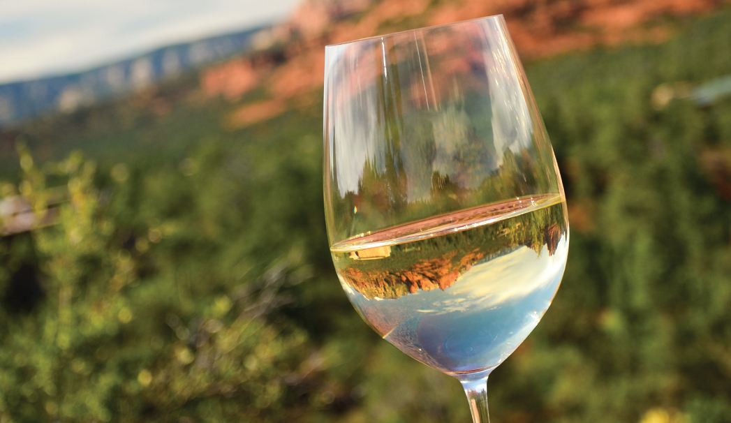 wineglass filled with wine in front of view of Sedona red rocks