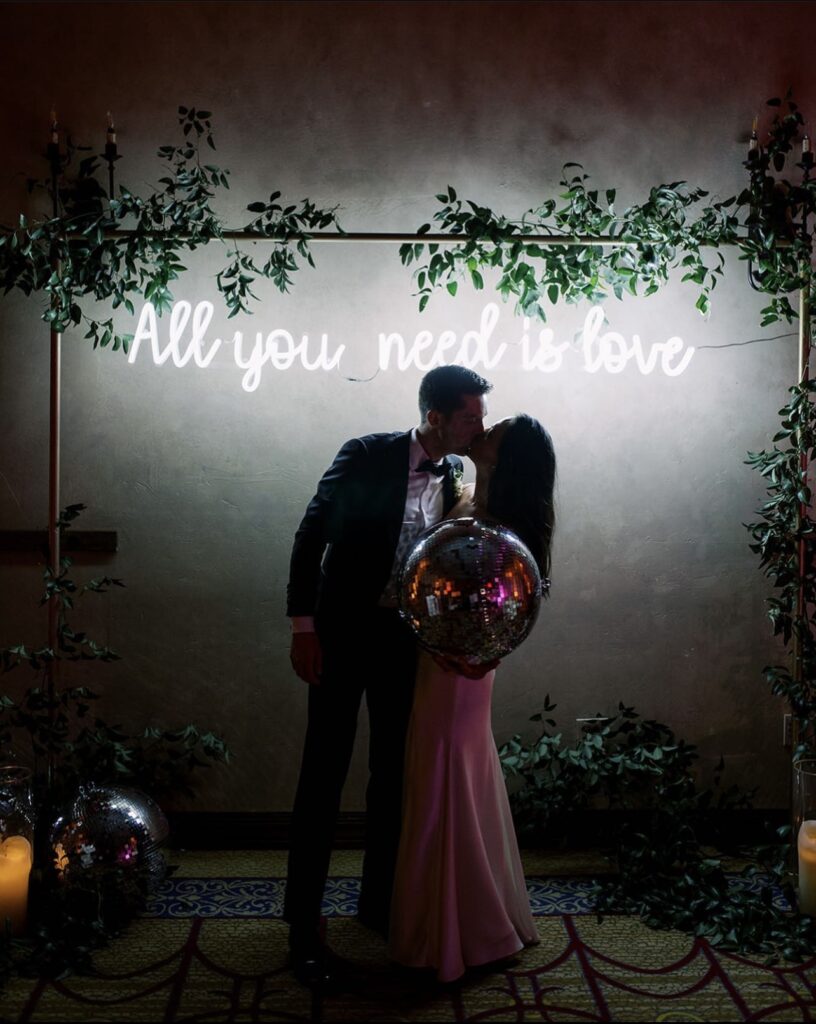 Bride and groom posing in front of back drop